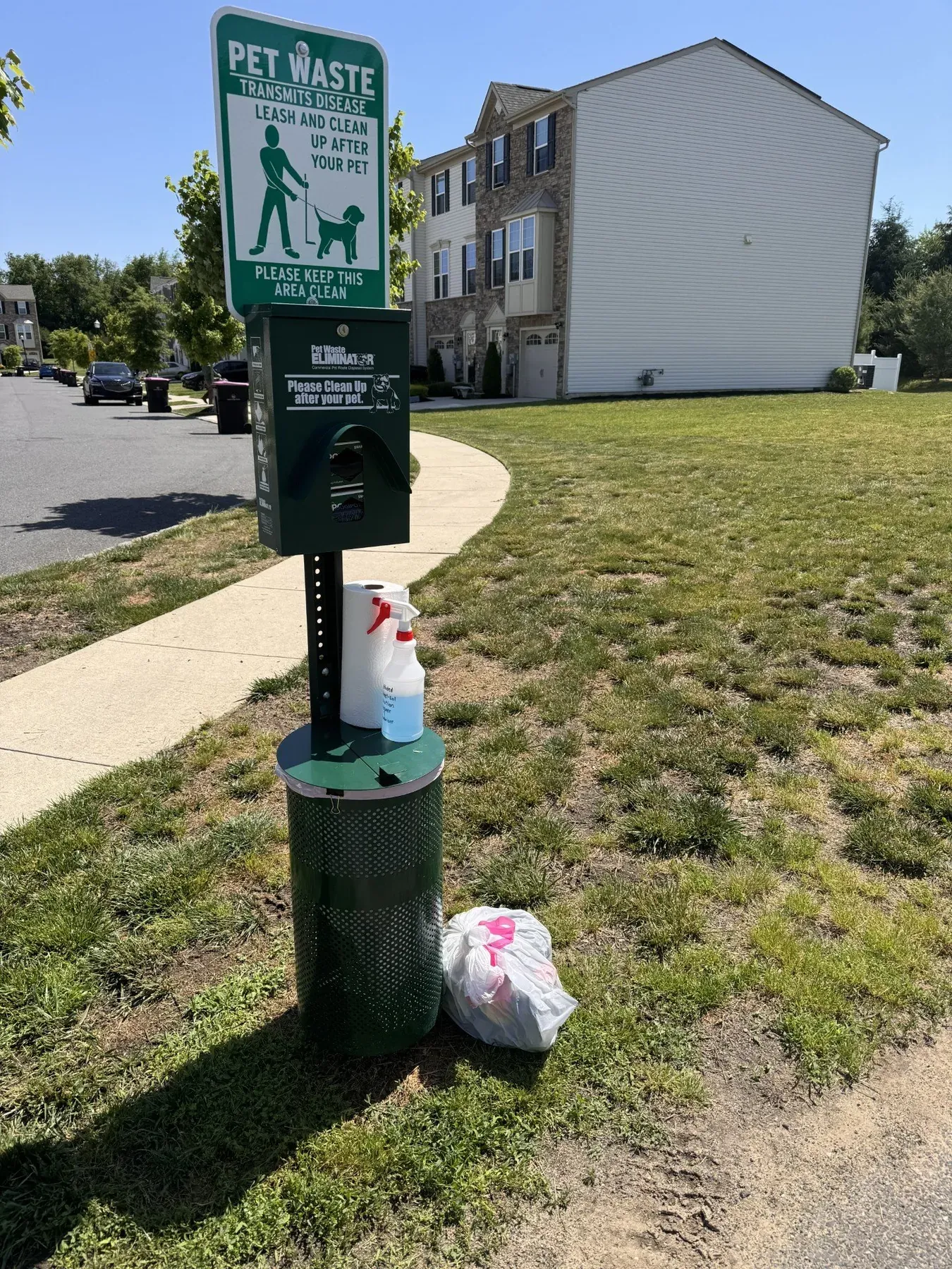 A pet waste station with bags beside a lawn at a New Jersey apartment community
