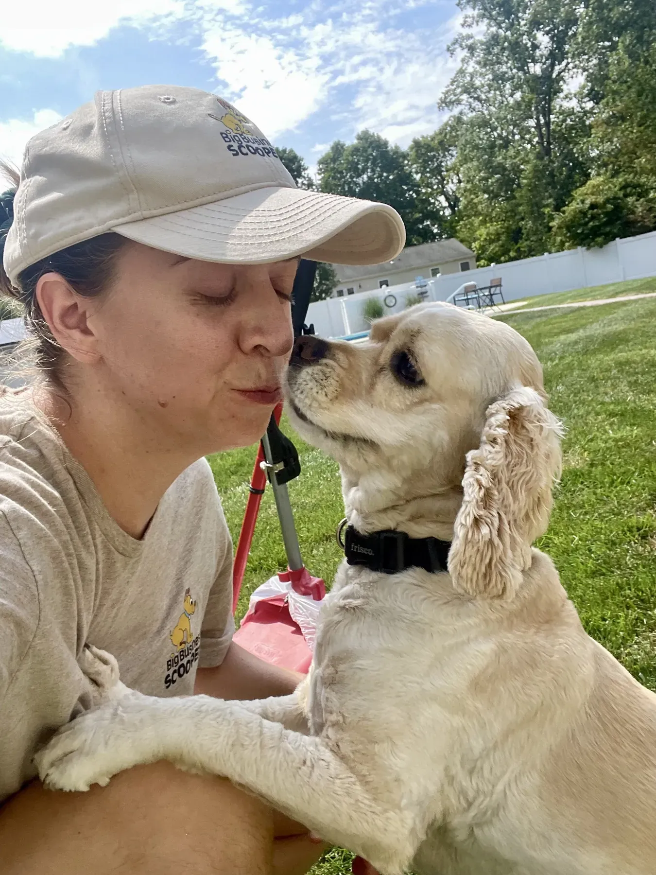 A Big Business Scoopers team member getting a kiss from a cocker spaniel during a visit