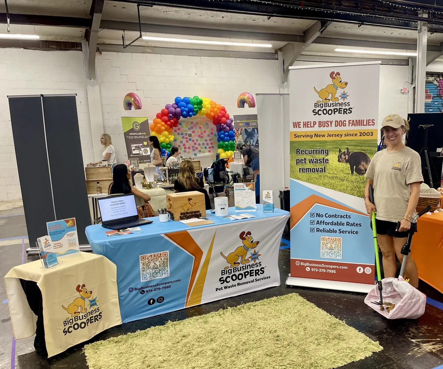 The Big Business Scoopers booth at an indoor pet expo, with a banner reading We Help Busy Dog Families